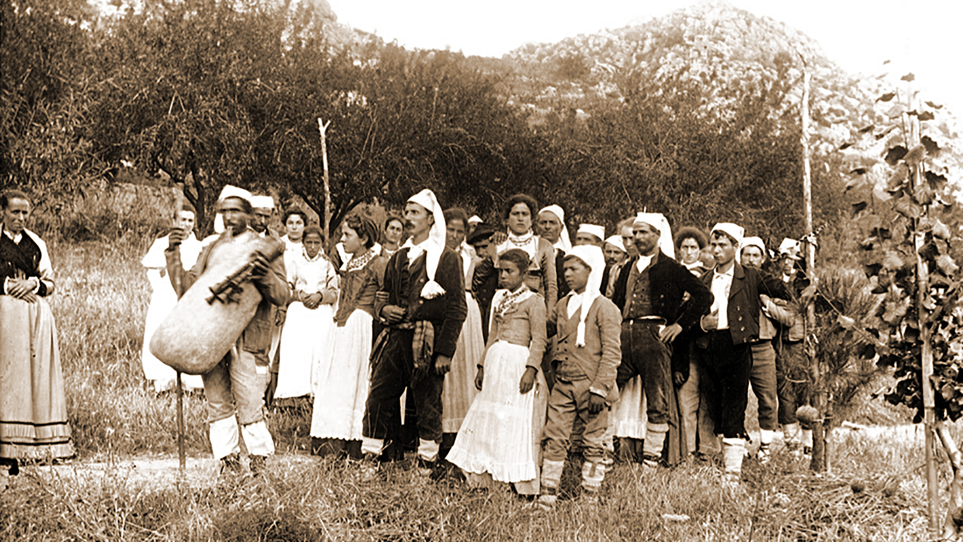 Un foto di Wilhelm von Gloeden di fine '800 che raffigura un gruppo di persone in costume siciliano dietro a un ciaramiddaru (zampognaro).